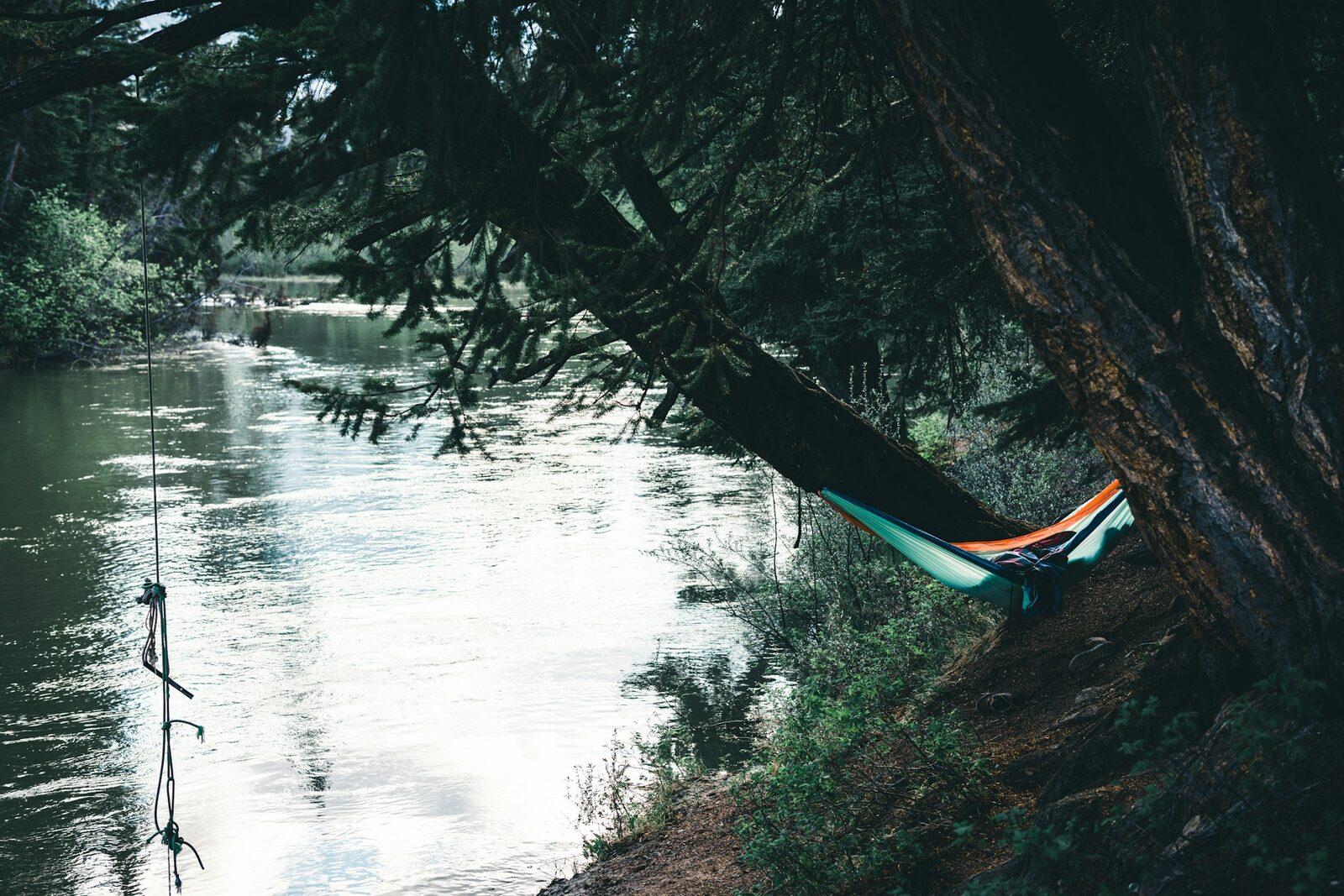 A hammock slung between trees beside a river